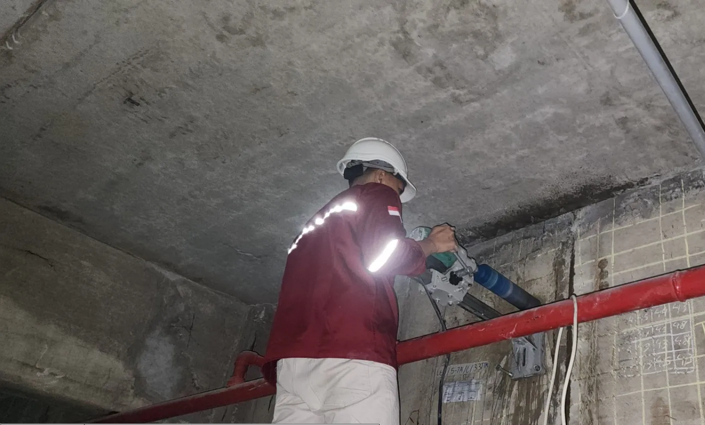 Teknisi melakukan core drill untuk pengambilan sampel inti pada dinding beton bangunan eksisting