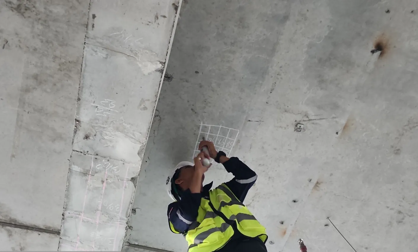 Teknisi melakukan Hammer Test pada sisi bawah pelat beton