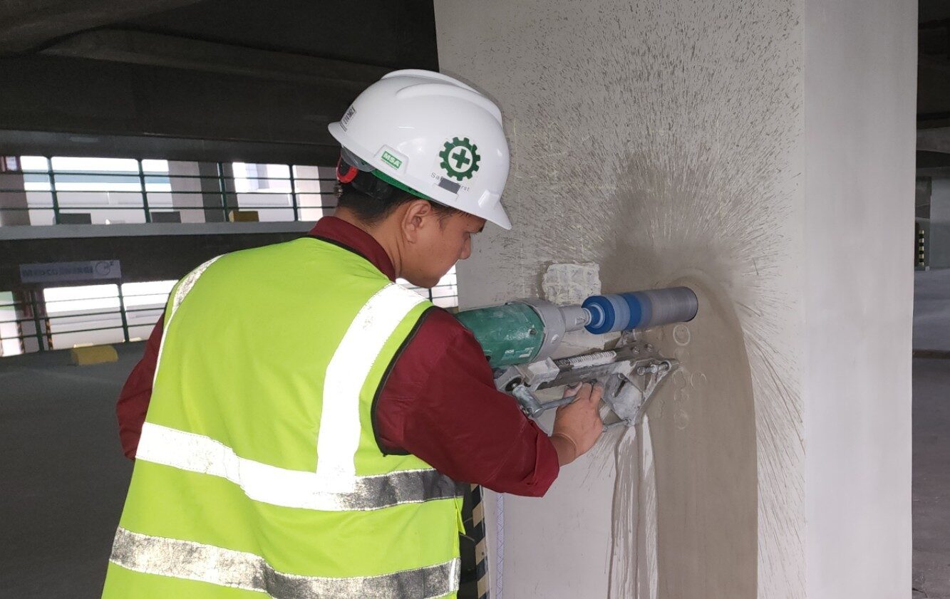 Teknisi mengoperasikan mesin core drill untuk mengambil sampel inti dari kolom beton